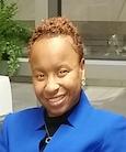 Headshot Woman in blue jacket smiling at the camera